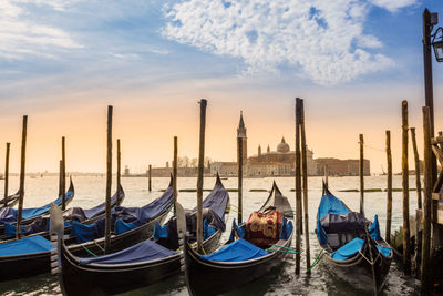 Boats moored in canal at sunset