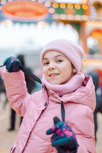 Little happy girl in pink at christmas fair. people buy gifts for holiday at christmas market