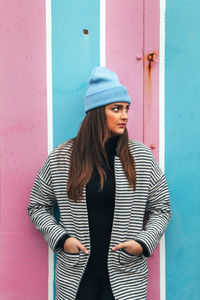 Beautiful young woman standing against wall