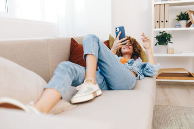 Portrait of woman using digital tablet while sitting on sofa at home