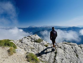 Rear view of man standing on rocks against mountain