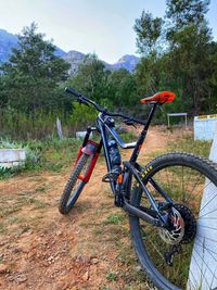 Bicycle parked on field by trees against sky