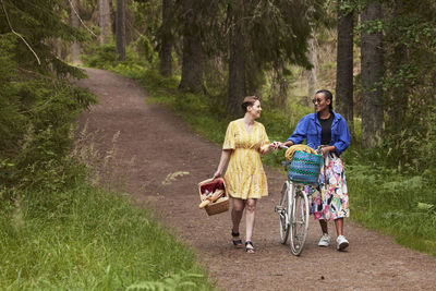 Female couple walking in forest with bicycle