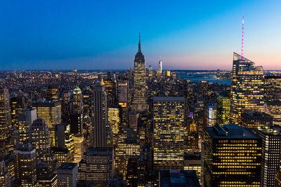 Empire state building amidst cityscape at manhattan during dusk