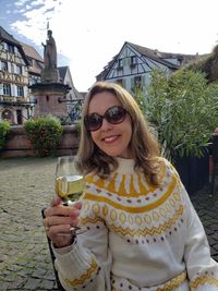 Portrait of smiling young woman with drink in front of building