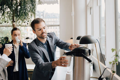 Businessman having coffee with female colleagues at creative office during break