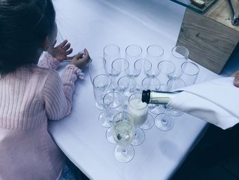 Cropped image of person pouring champagne in flute by girl