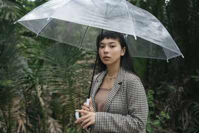 Mid adult woman holding wet standing outdoors during rainy season