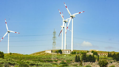 Low angle view of wind turbines on landscape against sky