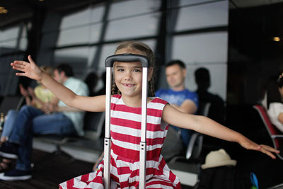 Girl sitting on trolley bag at airport