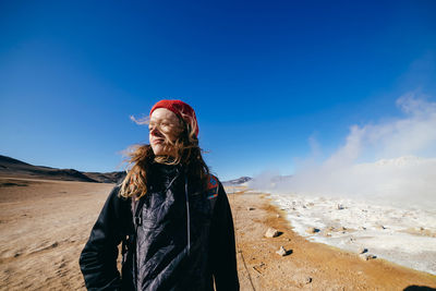 Portrait of young woman standing on snow covered land