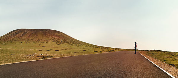 Country road amidst landscape against sky