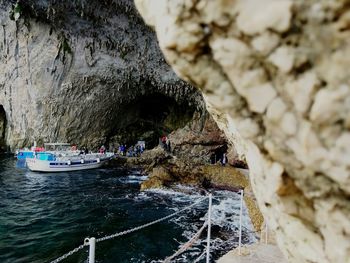 Boats on sea by rock formation