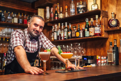 Portrait of man standing by bottles