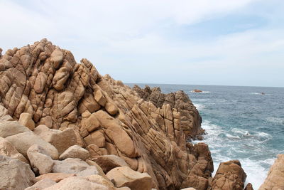 Rock formation on beach against sky