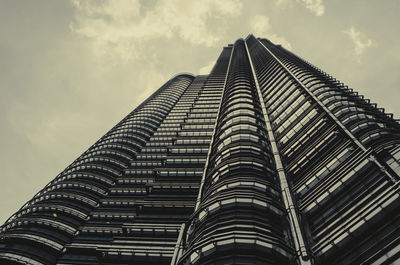 Low angle view of skyscrapers against cloudy sky