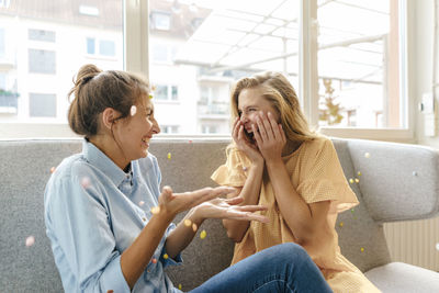 Two carefree young women sitting on couch