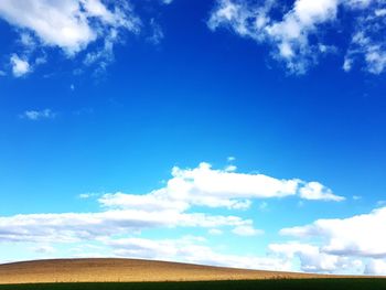Low angle view of landscape against blue sky