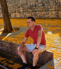 Portrait of young man sitting on footpath