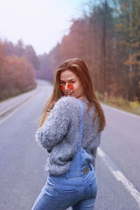 Portrait of woman standing on road against trees