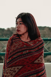 Young woman looking away against clear sky