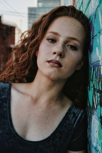 Close-up portrait of teenage girl leaning on wall outdoors