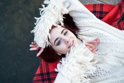 Smilling girl in sweater lying on a pier by natureal lake in autumn.