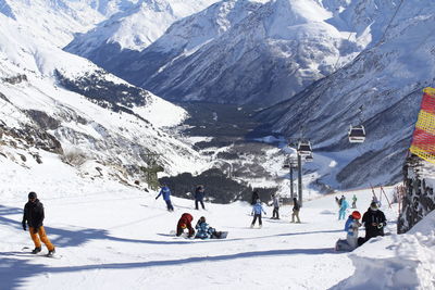 People on snow covered field against mountains