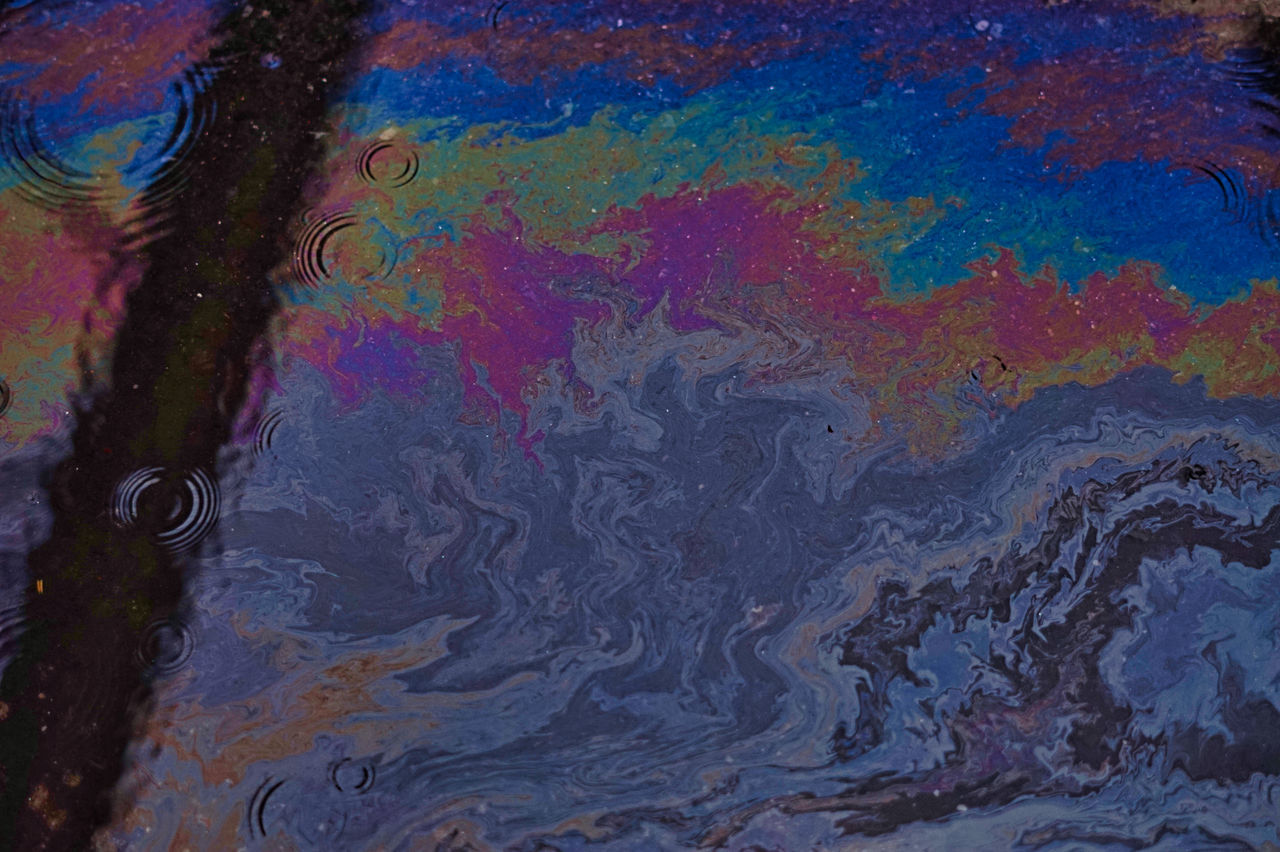 HIGH ANGLE VIEW OF MULTI COLORED WATER ON WET SHORE