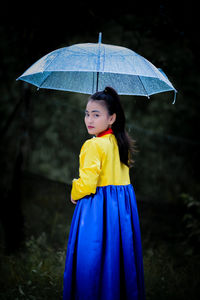 Portrait of woman with umbrella standing in forest