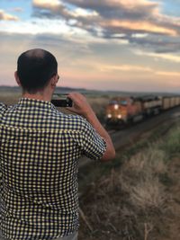 Rear view of man standing against sky during sunset