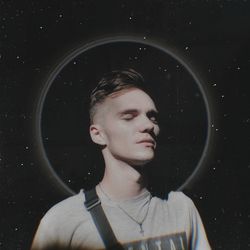 Portrait of young man looking away against black background