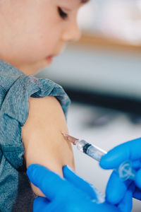 Cropped hands of doctor injecting syringe to boy in hospital