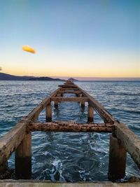 Pier over sea against sky during sunset