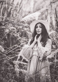 Portrait of young woman standing by tree