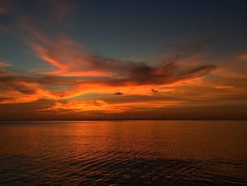 Scenic view of sea against dramatic sky during sunset