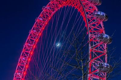 Low angle view of illuminated ferris wheel against sky at night