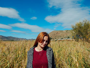 Woman looking away while standing on land against sky