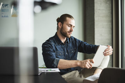 Businessman sitting in office using tablet