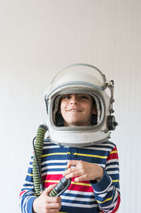 Portrait of smiling boy holding camera over white background