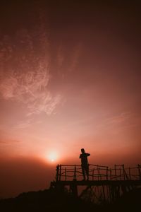 Silhouette man standing against orange sky