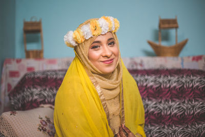 Portrait of smiling young woman in traditional clothing and flowers at home