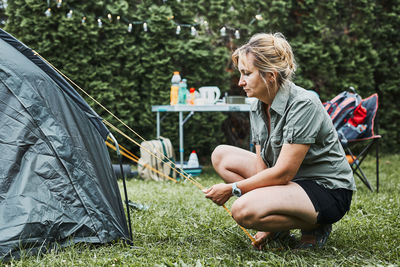 Woman putting up a tent at camping during summer vacation. female preparing campsite to relax