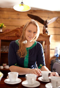 Portrait of beautiful woman by table with cups at home