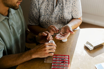 High angle view of senior woman taking medicine while sitting with male nurse at home