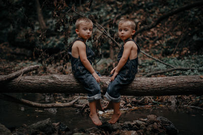 Full length of siblings sitting on wood