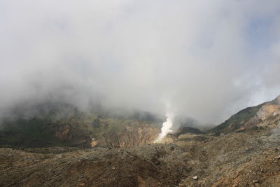 Smoke emitting from volcanic mountain against sky