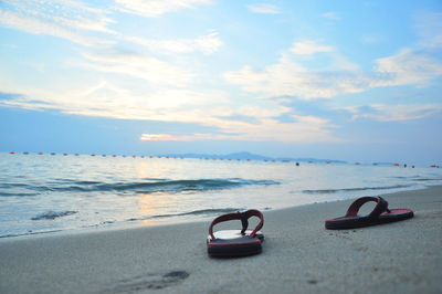 View of shoes on beach against sky