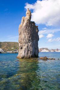 Rock formation in sea against sky