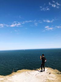 Full length of woman standing on sea against blue sky